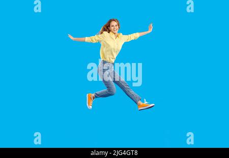 Full length body size view of nice attractive lovely glad cheerful wavy-haired woman jumping having fun rising hands up isolated on blue color Stock Photo