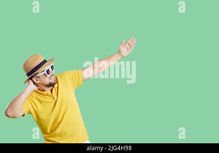 Happy cheerful young man in summer clothes rejoices and having fun on light green background. Stock Photo