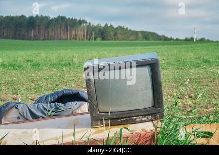 Old TV on the field near fores green grass summer Stock Photo