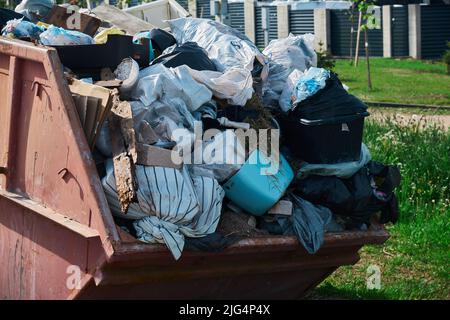 Large loaded red metal container full of construction waste for disposal Huge pile of garbage demolition removal Stock Photo