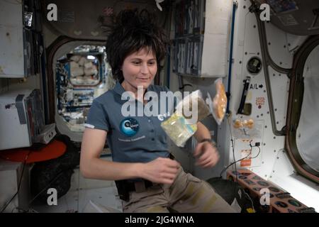 International Space Station Expedition 67 Flight Engineer Samantha Cristoforetti of the ESA, poses with food packets flying weightlessly inside the Unity module aboard the orbiting spacelab, July 2, 2022 in Earth Orbit. Stock Photo