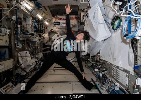 International Space Station Expedition 67 Flight Engineer Samantha Cristoforetti of the ESA, exercises and practices yoga maneuvers while attached to hand and foot rails inside the Kibo laboratory module aboard the orbiting spacelab, June 21, 2022 in Earth Orbit. Stock Photo