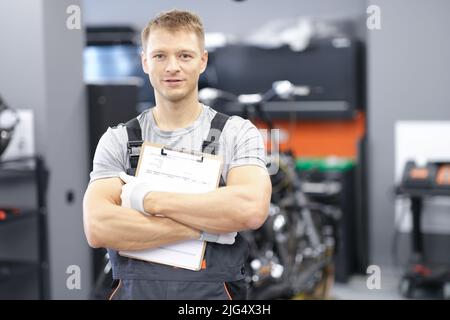 Male car mechanic holding clipboard in auto workshop Stock Photo