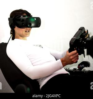 A gamer woman is sim racing with a high end simracing reck Stock Photo