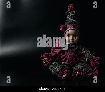 Amazing realistic porcelain doll, toy, harlequin, selective focus, vintage concept, space for text Stock Photo