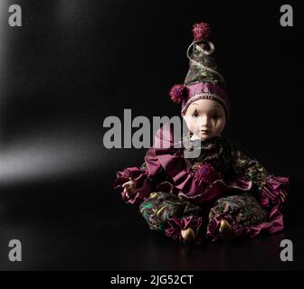 Amazing realistic porcelain doll, toy, harlequin, selective focus, vintage concept, space for text Stock Photo