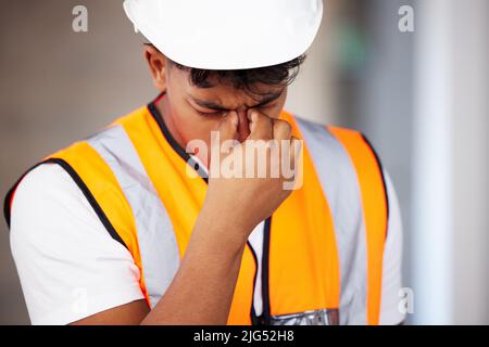 Ill need a painkiller. Shot of a young contractor suffering from a headache while working. Stock Photo