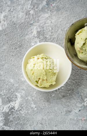 Two scoops of pistachio ice cream in bowls on light surface Stock Photo