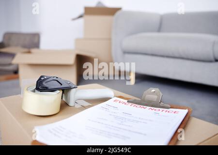 Onto the next adventure. Shot of an eviction notice and a tape dispenser on a cardboard box in an empty living room. Stock Photo