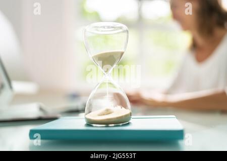 Late Invoice And Billing Deadline With Hourglass At Desk Stock Photo