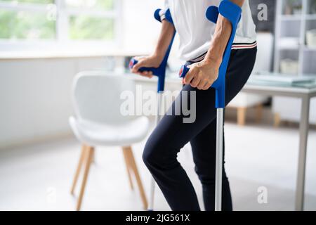 Disabled Woman Using Crutches To Walk At Home Stock Photo