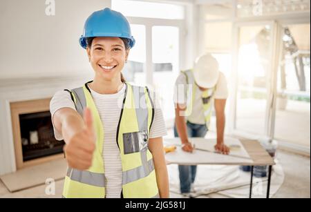 Your living space is going to look great. Shot of an attractive young construction worker standing inside and making a thumbs up gesture. Stock Photo