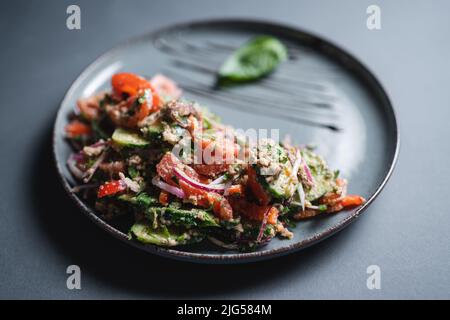 georgian salad with fresh tomato, cucumber, onion and walnut on black background Stock Photo