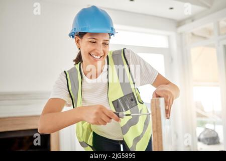 I need these screws to be tight. Shot of an attractive young construction worker standing alone and using a screwdriver. Stock Photo