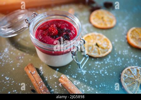 closeup of berry panna cotta dessert with cherry sauce in glass jar on table Stock Photo