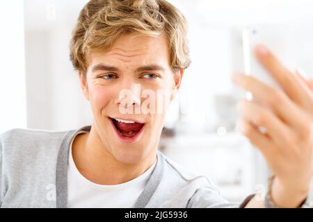 Am I cute yet. Shot of a young woman making funny faces while taking selfies with his smartphone. Stock Photo