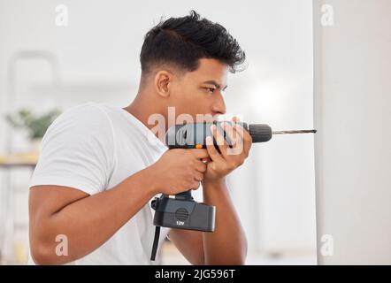 This is where I need the hole. Shot of a man using a cordless drill on a wall. Stock Photo
