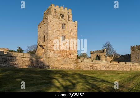 King James IV tower at Ford Castle, Northumberland in warm evening sunlight with a clear blue sky and near full moon. Stock Photo