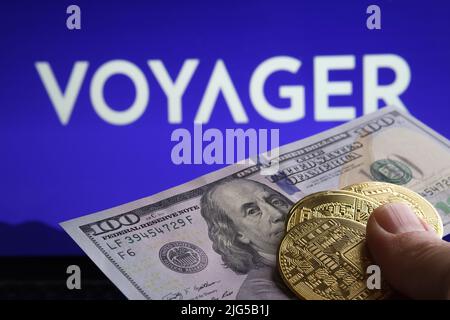 100 US dollars crypto tokens seen in front and blurred Voyager Digital Ltd company logo on blurred background. Concept. Stafford, United Kingdom, July Stock Photo