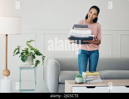 Washed, folded and ready for use. Shot of a young woman doing laundry at home. Stock Photo