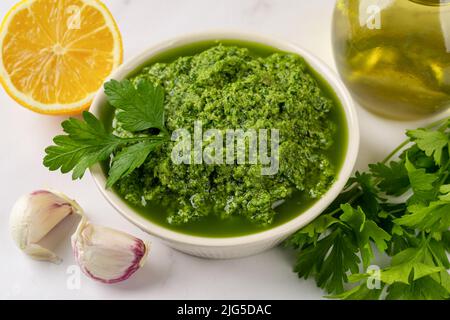 Chimichurri dipping sauce in a bowl. Fresh green sauce from parsley, garlic cloves, olive oil and lemon juice. Freshly made salsa verde close-up. Stock Photo