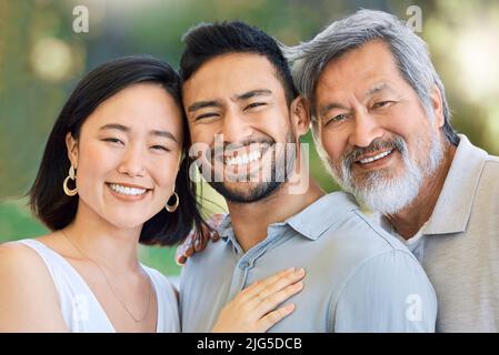 Happiness is at the heart of family. Shot of a happy young man and woman spending time with their elderly father in a garden. Stock Photo