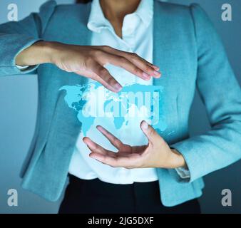 Focused on growth. Cropped shot of an unrecognisable businesswoman standing alone in the office and holding a cgi globe. Stock Photo