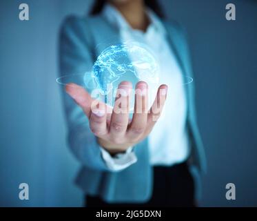 Taking this business global. Cropped shot of an unrecognisable businesswoman standing alone in the office and holding a cgi globe. Stock Photo