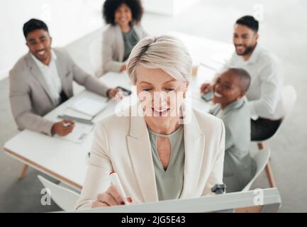 Thinking of new concepts. Shot of a mature businesswoman writing on a whiteboard during a meeting at work. Stock Photo