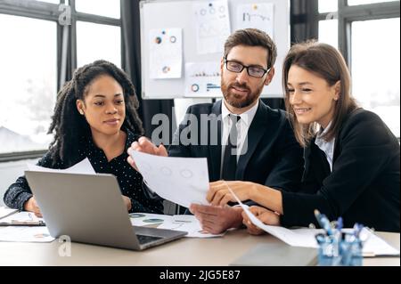 Positive diverse people, multiracial business team working together in office meeting room, are brainstorming, sharing ideas, discussing project, startup, make decisions, analyze financial documents Stock Photo