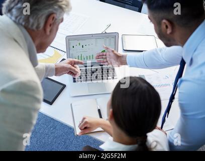 The proof is in the numbers. Shot of a group of businesspeople discussing something on a laptop. Stock Photo