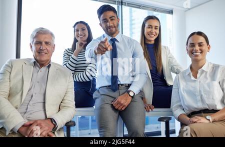 We want you on our team. Shot of a group of businesspeople posing together in an office. Stock Photo