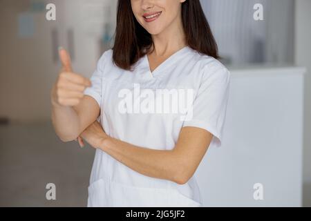Close up of nurse standing near the reception in a medical clinic and showing thumb up Stock Photo