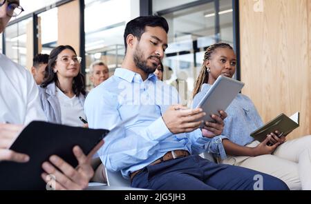 Looking over his notes. Cropped shot of a group of businesspeople sitting in the conference room during a seminar. Stock Photo