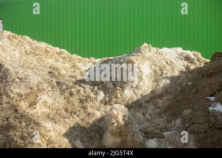 Dirty snow on road. Large snowdrift. Snow removed from road. Dirty pile. Stock Photo