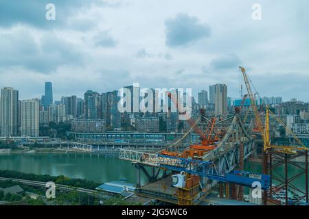 This is Chongqing, China, where a bridge is being built over a large river.  This bridge will connect the two sides of the river and make the traffic Stock Photo
