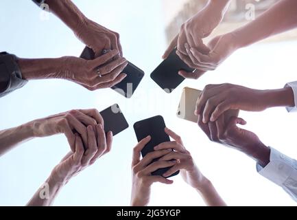 Were making money. Cropped shot of a group of unrecognizable businesspeople using their cellphones. Stock Photo