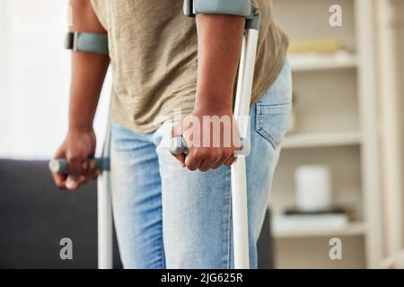 Lifes ups and downs. Shot of a unrecognizable man using crutches at home. Stock Photo