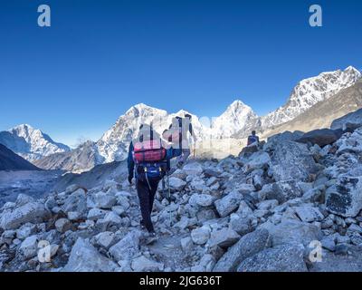 Ttekkers crossing the moraine to Lobuche from Gorak Shep on a clear May morning after returning from Everest Base Camp, Khumbu. Stock Photo