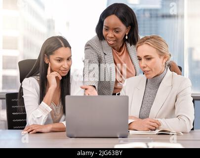 Days like these are what I live for. Shot of a group of businesswomen working together while using a laptop. Stock Photo