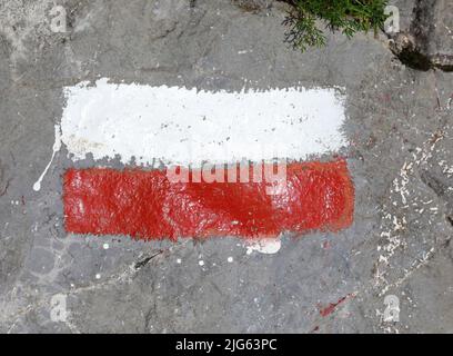 two wide colored stripes of white and red to signal the path in the mountains on a rock Stock Photo