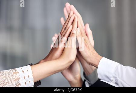 Getting down to business as a dedicated team. Closeup shot of a group of businesspeople joining their hands together in a huddle in an office. Stock Photo