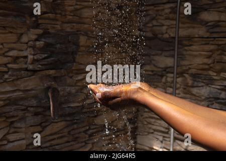 Cropped hands of african american young woman cupping shower water in bathroom at home Stock Photo