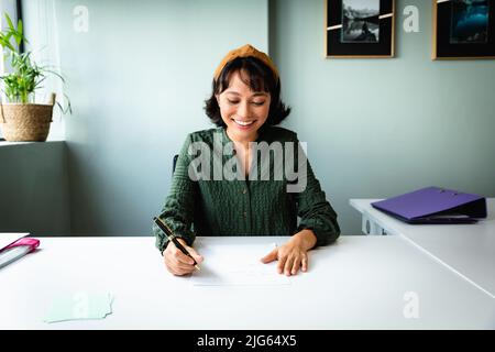 Smiling young asian creative businesswoman working at desk in office Stock Photo