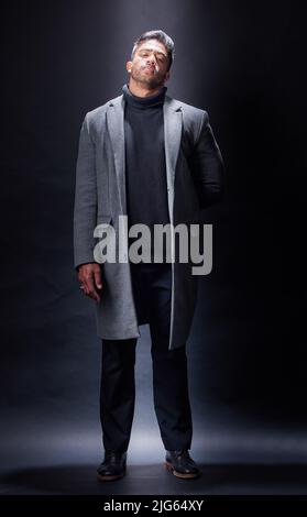 Wear what you want with confidence. Studio portrait of a handsome and fashionable young man posing against a dark background. Stock Photo