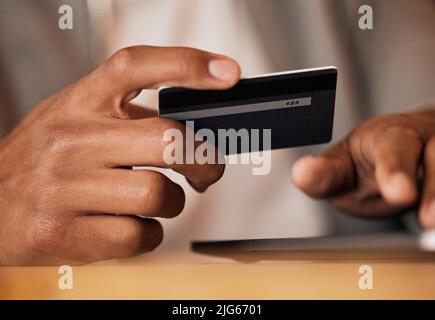 .. Man holding credit card and using tablet. Closeup of mans hands holding bank card while doing online shopping or mobile banking on his digital Stock Photo