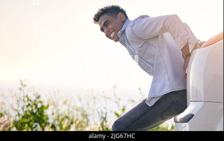 Maybe a push will help.... Full length shot of a handdsome young man pushing his car after suffering a vehicle breakdown. Stock Photo