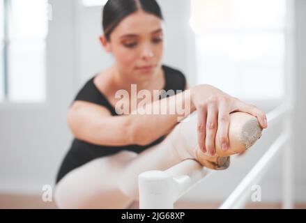 Ballet engages the entire body from head to toe. Shot of a young ballet dancer leaning against a barre. Stock Photo