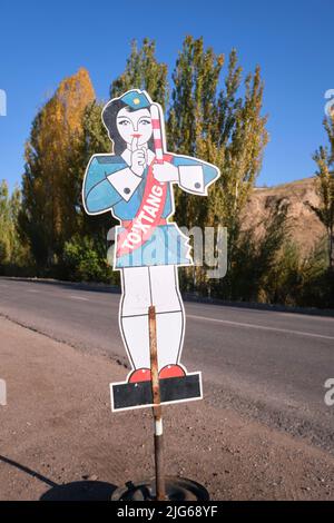 A metal cartoon, cutout, painted sign of a safety officer at a school crossing on a rural, country road, street. In Parkent, near Tashkent, Uzbekistan Stock Photo
