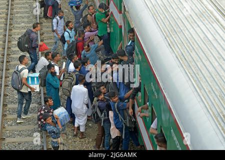 Dhaka. 8th July, 2022. Travelers try to climb up a train at a railway station in Dhaka, Bangladesh, July 7, 2022. As Eid al-Adha festival approaches, many people from Bangladesh capital Dhaka have streamed out of the city to join the festival with their kith and kin in village homes. Credit: Xinhua/Alamy Live News Stock Photo